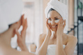 Attractive latina woman with under eye patches looking at mirror during daily skincare treatment - PhotoDune Item for Sale