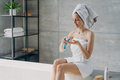 Woman apply natural skincare cosmetics sitting in modern bathroom. Body care treatment after shower - PhotoDune Item for Sale