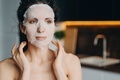 Female with naked shoulders uses rejuvenation facial sheet mask. Skin treatment at home, skincare - PhotoDune Item for Sale