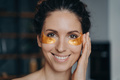 Smiling latina woman applying moisturizing golden under eye patches at home. Skincare beauty routine - PhotoDune Item for Sale