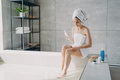 Female massaging leg using natural anticellulite skincare cosmetics in bathroom. Body care treatment - PhotoDune Item for Sale