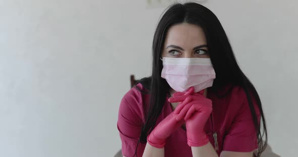 Tired Nurse in Protective Form Relaxes on Chair with Leaned Hands and Thinking