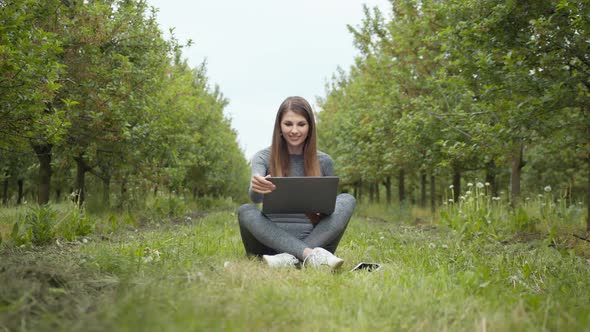 Girl Sitting in Park or Forest Opening Laptop on Nature