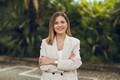 Smiling woman in blazer standing near tropical garden - PhotoDune Item for Sale