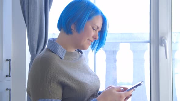 Young girl with blue hair using modern smartphone for communication online in 4k video