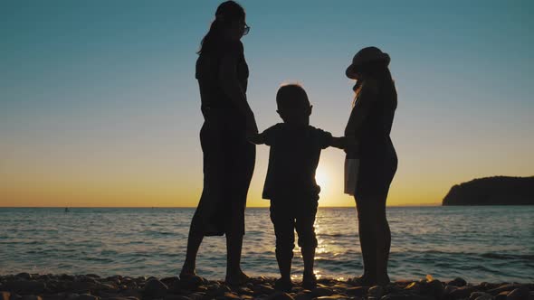 Happy Family Mother with Two Children on Vacation at the Beach. Silhouette Mother with Two Children