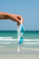 Hand holds swimming goggles agaist seascape. Tropical vacation concept. - PhotoDune Item for Sale