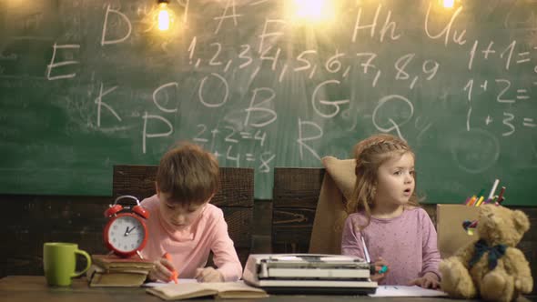 Pupils in Elementary School. Kids in Classroom. Boy and Girl Sitting at Desk and Writing a Text