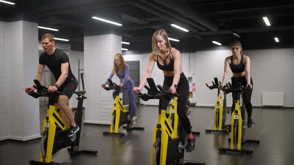 Group of People is Training on a Spin Bikes Performs Aerobic Endurance Training on the Simulators in