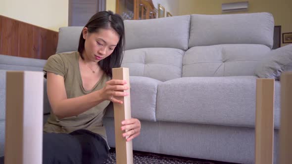 Asian woman assembling table in living room