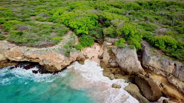 Dolly out aerial view of a couple on a hidden beach in Westpunt, Curacao, Dutch Caribbean island