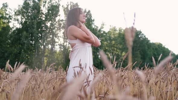 An Attractive Girl Stands in the Field. Shooting Through the Ears