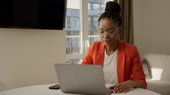 Young African American Woman Opening a Laptop and Starts Working in Her Apartment