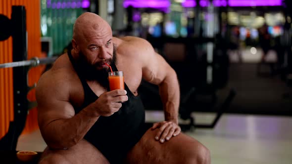 Muscular Man Drinking Refreshing Juice From a Glass After a Workout in the Gym Health Care