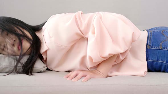 Close up Asian woman jumping down on sofa and sleeping at home after getting tired from work