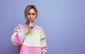 cute blond woman in casual striped sweater asking to be quiet covering her mouth with finger on - PhotoDune Item for Sale