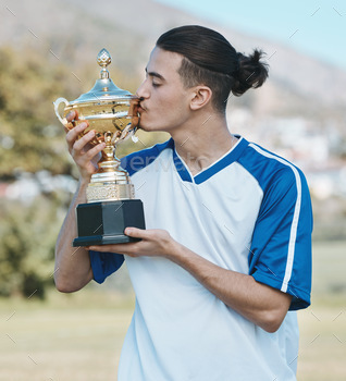 Soccer player, celebrate and competition with trophy in the outdoor with a kiss after win. Sports p