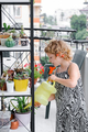 Girl watering plants from a watering can on balcony, taking care of home plants - PhotoDune Item for Sale