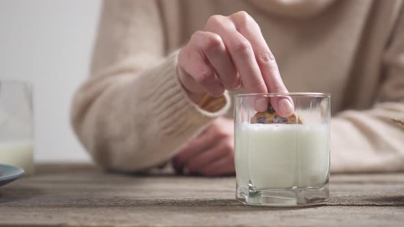 A Girl In A Warm Beige Sweater Dips Cookies In Milk