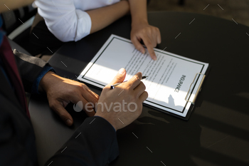 ance policy and pointing with a pen where the policyholder must to sign. Insurance agent presentation and consulting insurance detail to customer.