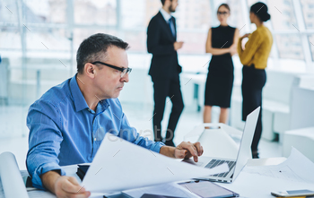 Skilled businessman in spectacles working online with text documents