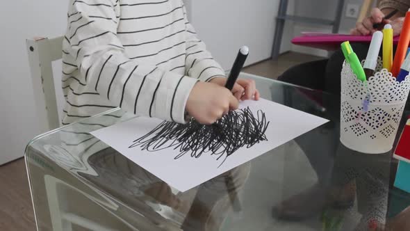 Unrecognizable kid drawing black strokes