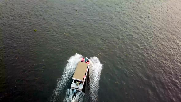 Boat With Passengers Cruising In The Calm Lake. - aerial