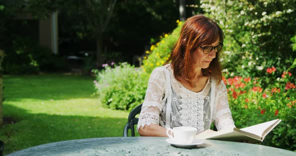 Mature woman reading a book in the garden 4k