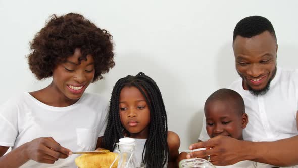 Happy family having breakfast together on bed