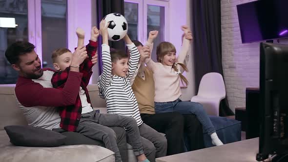 Family Football Fans Sitting on the Sofa at Home and Celebrating the Victory