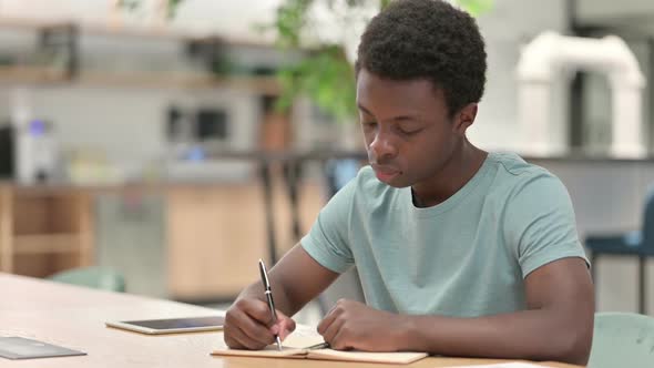 Young African Man Writing on Paper