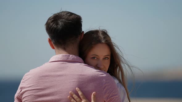 a Woman with Long Hair Puts Head on the Shoulder of a Man in a Pink Tshirt and Looks From Behind His