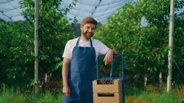 Young Farmer Showing Berry Harvest at Summer Season in Orchard Plantation House