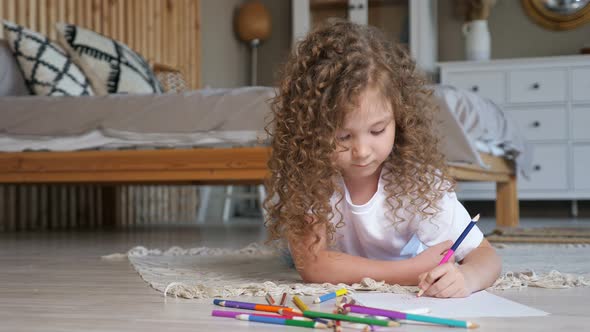 Little Preschooler Girl with Long Loose Curly Hair Draws