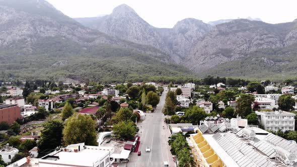 Aerial View of a Beautiful Town Among Trees at the Foot of the Mountains and Busy Traffic on the