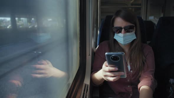 Woman in mask on the train using a phone