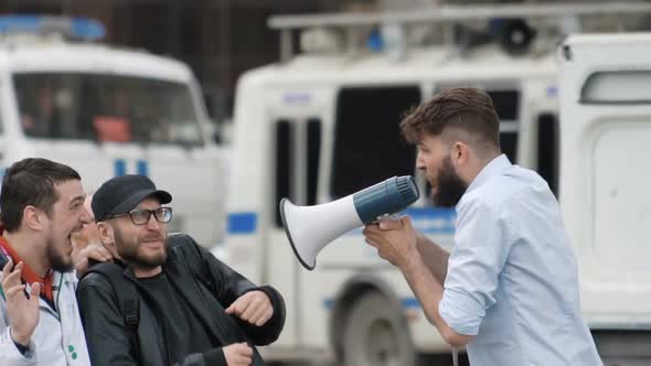 An Angry Man with a Beard Shouts Loudly at People in a Megaphone.