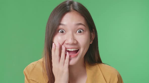 Young Asian Woman Opening Her Eyes With Palms , Surprised And Saying Wow In The Green Screen Studio