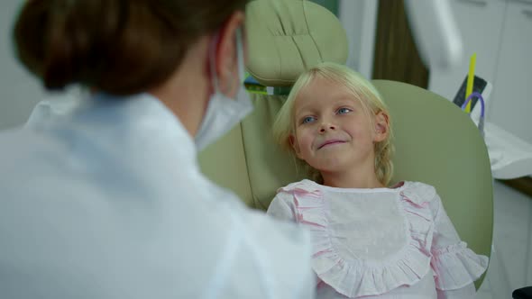 Girl Listens To the Kind Dentist and Smiles.