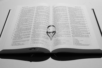 Ring on an open book forming a heart shape shadow on the pages