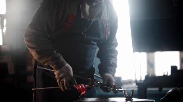 Blacksmith Workshop  a Man Works with Heated Detail Using Forceps