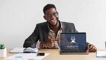 Young black man wearing eyeglasses working on laptop, using chatbot