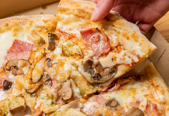 Closeup shot of a female's handpicking a slice of pizza in a box