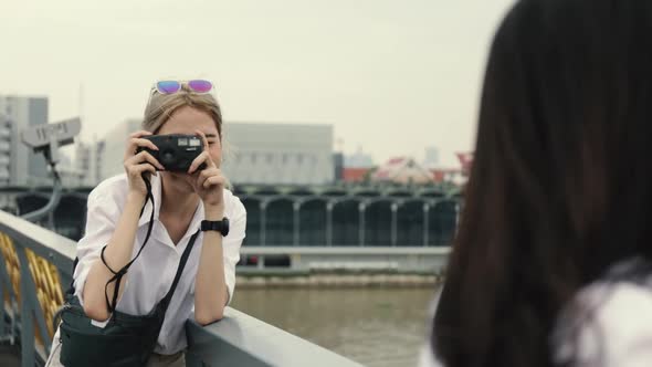 Asian lesbian couples enjoying traveling using film camera taking a photo.