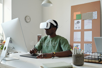 Young graphic designer in extended reality headset using stylus and touchpad