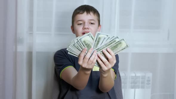 Happy Child Holds a Lot of 100 Dollar Bills in Hands Clutching Them to Chest