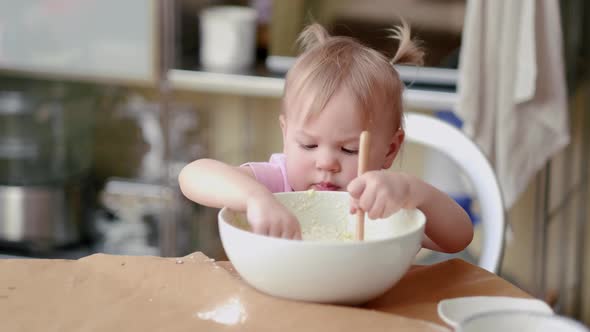 Little Cute Funny Girl Licking the Dough From Her Finger Helping Mother Prepare Pie Cake in Kitchen