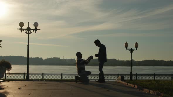 Gay Marriage Proposal Concept. Silhouette of Two Men. Guy Gifts a Wedding Ring To His Fiance