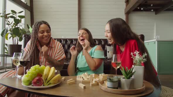 Multiracial Women Playing Board Game Drinking and Relaxing Indoors