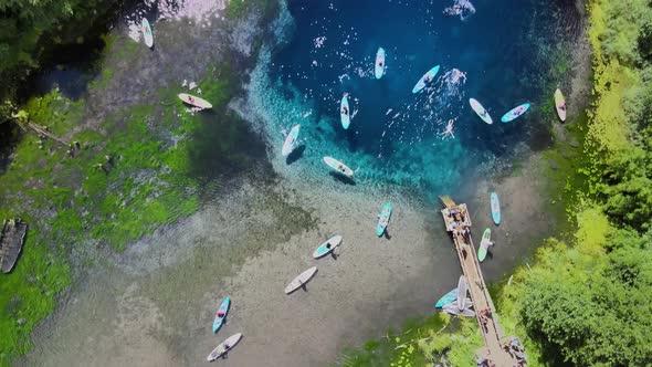 Tourists walk along the clear water on sup. A diver dives into the water.